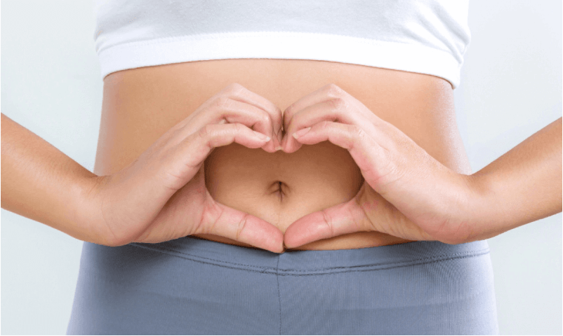A woman making a heart with her hands over her tummy
