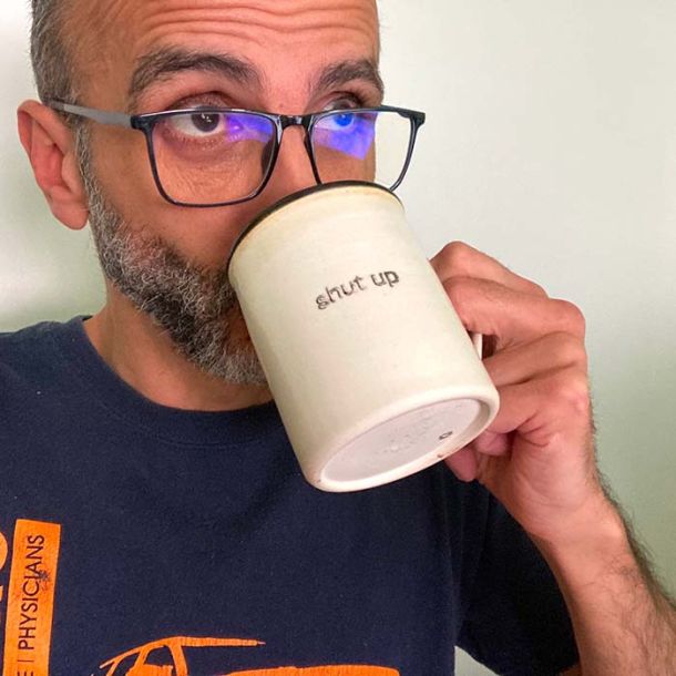 Anthony Sanna drinking coffee from a cup that says shut up