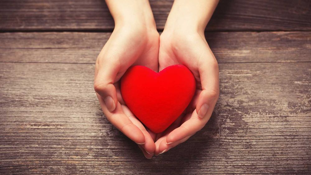 Cupped hands holding a red felt heart